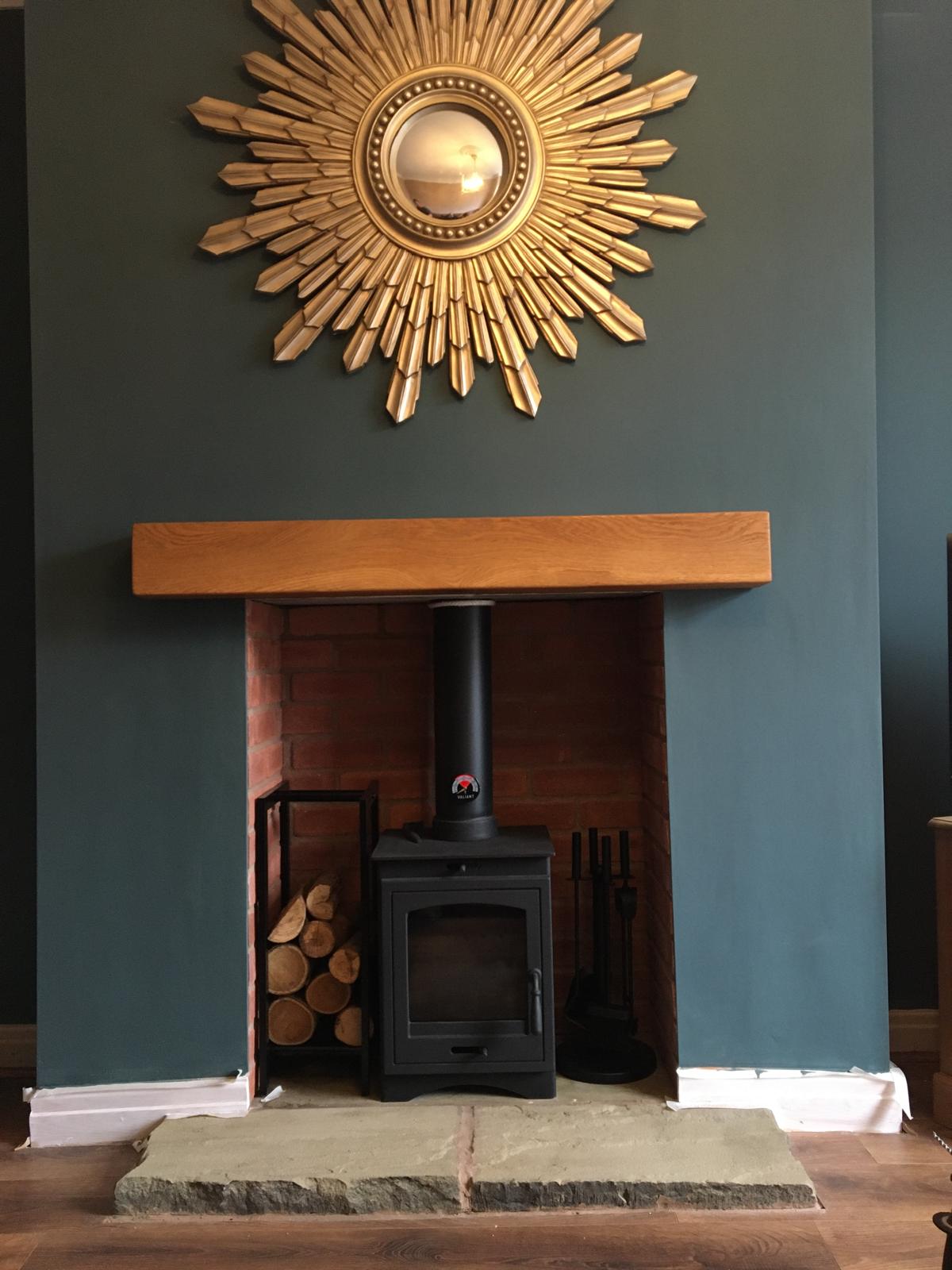 Stove with oak beam mantel and green feature wall